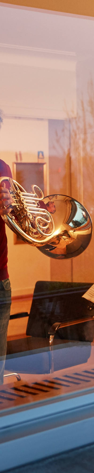 Man playing horn in his living room at dusk
