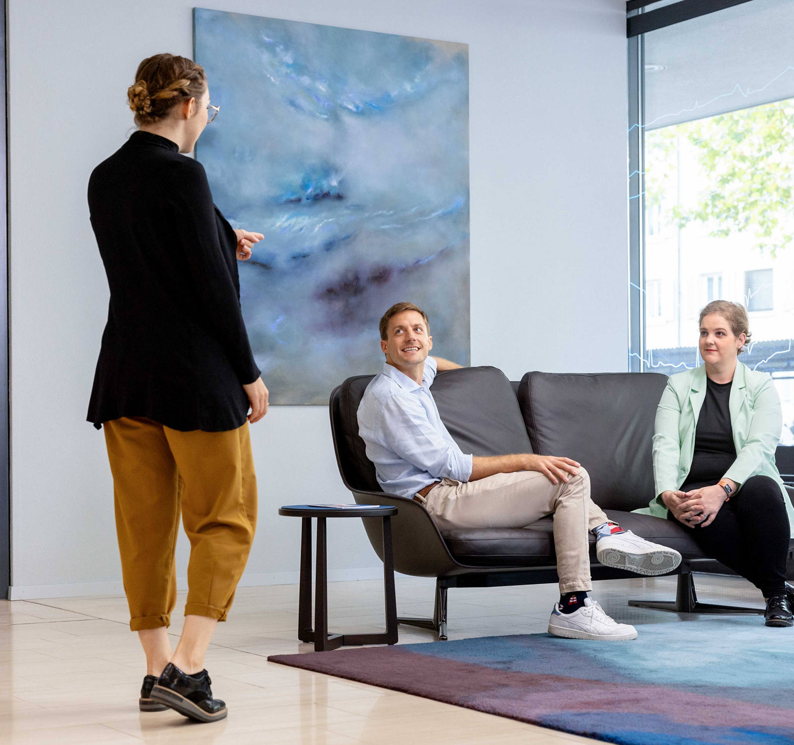 Une femme va chercher deux personnes qui les attendent dans l’entrée du siège principal de la CSS.