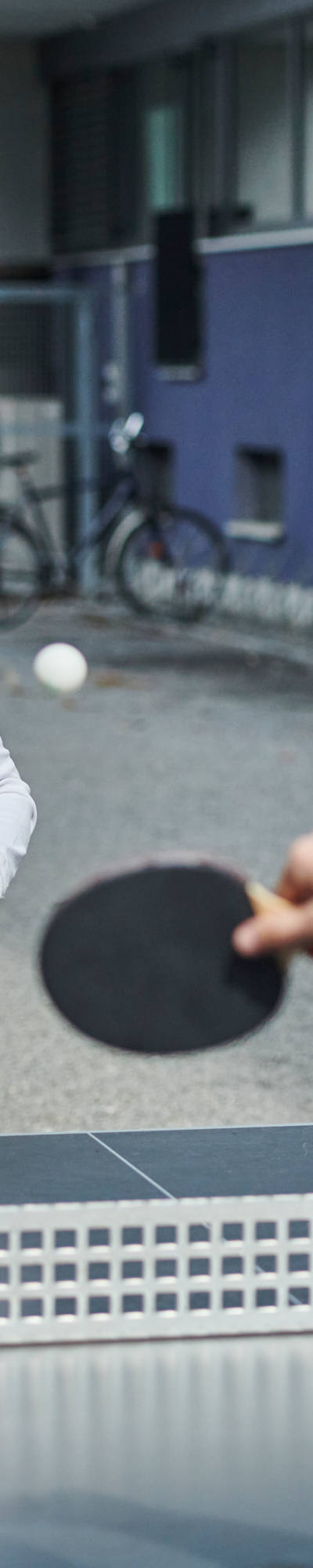 Deux collaboratrices et collaborateurs jouent au ping-pong dans la cour intérieure de la CSS.