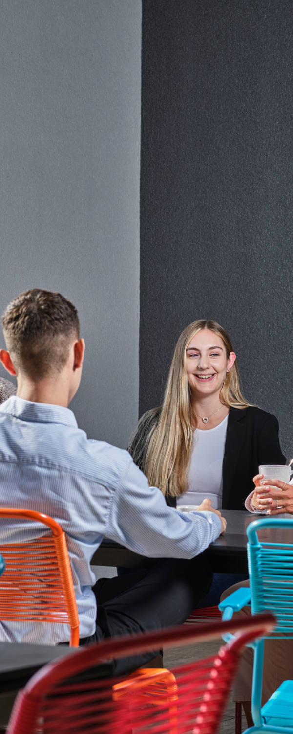 Un gruppo di colleghi di lavoro sono seduti sulle colorate sedie outdoor della terrazza CSS e si godono una pausa.
