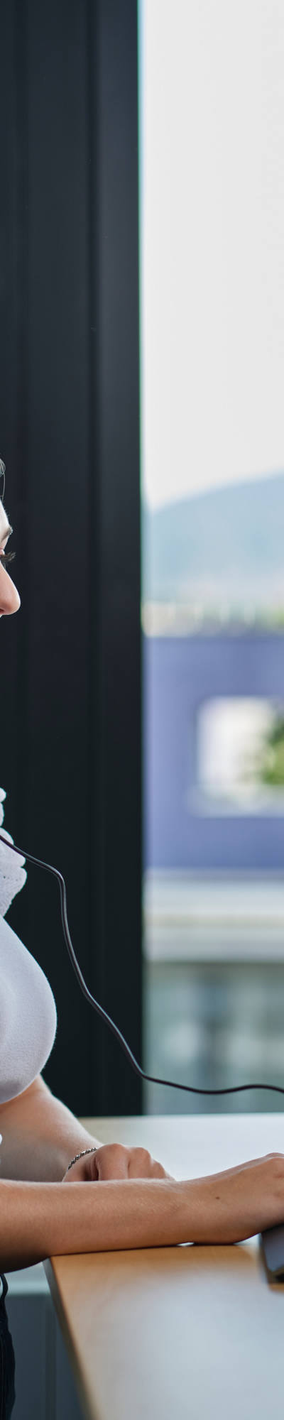 Eine Frau mit Headset arbeitet an ihrem Computer.