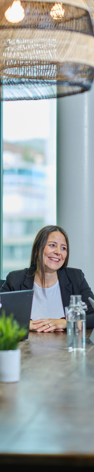 Drei Frauen sitzen mit ihren Laptops an einem grossen Holztisch.