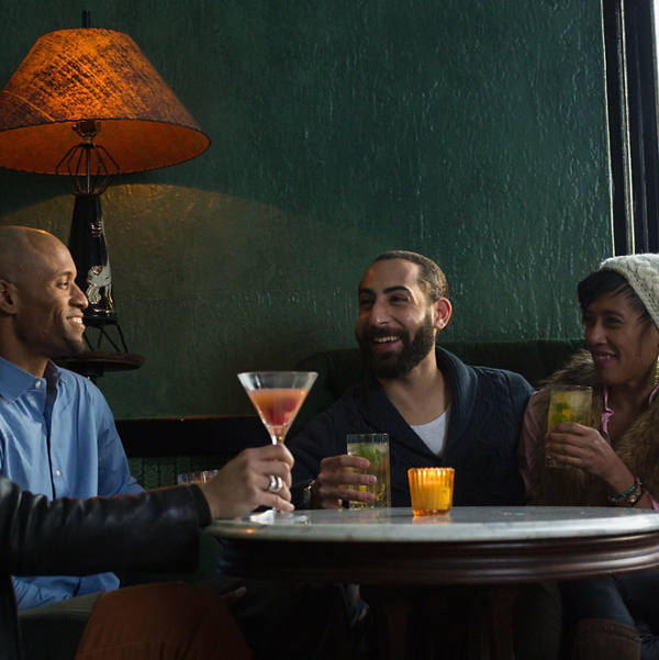 Eine Gruppe Menschen sitzt in einem warmen Lokal und geniesst die gute Zeit bei einem Drink.