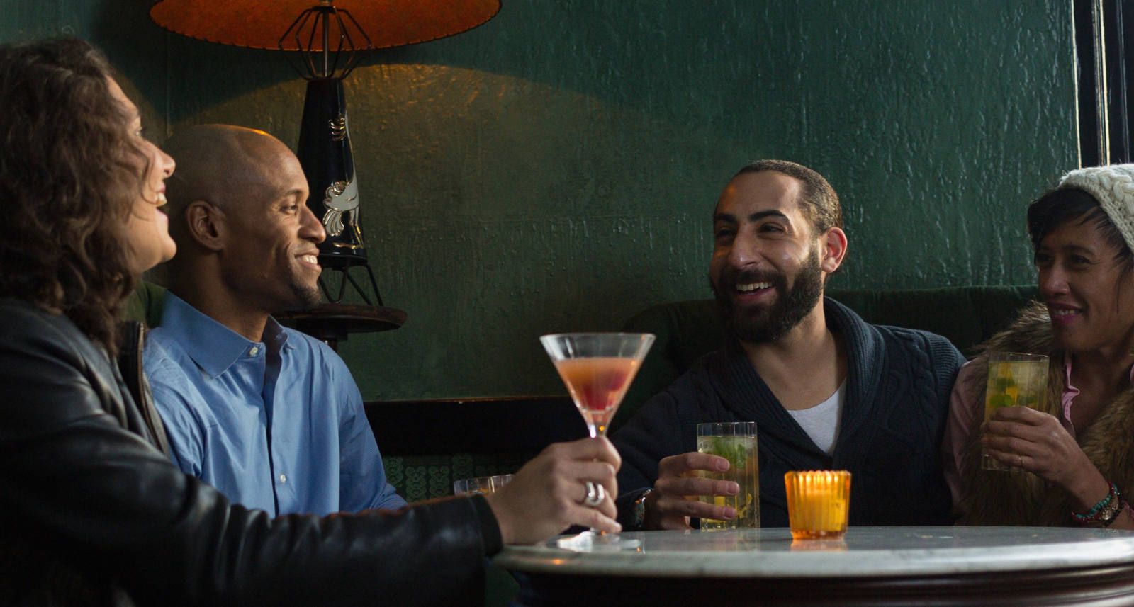 Eine Gruppe Menschen sitzt in einem warmen Lokal und geniesst die gute Zeit bei einem Drink.