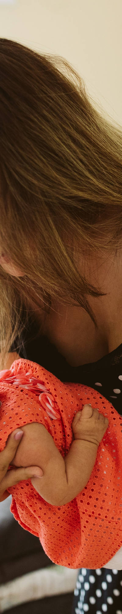 Mother stands in the nursery holding her newborn child and looking at it lovingly.