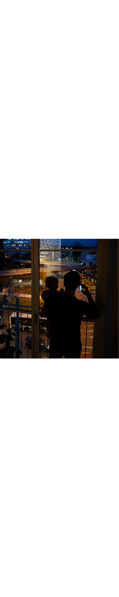 Papà telefona con il bambino in braccio di notte.