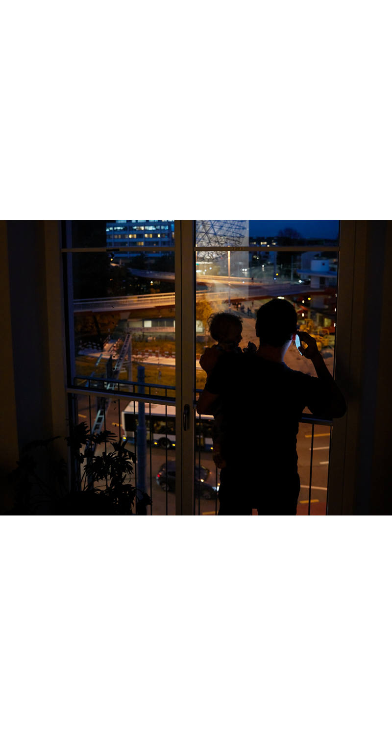 Father on the phone with child on his arm at night.