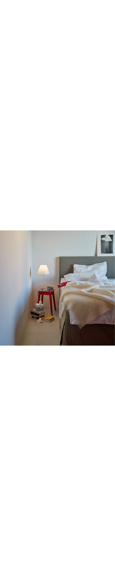 A burning bedside lamp stands next to the bed.