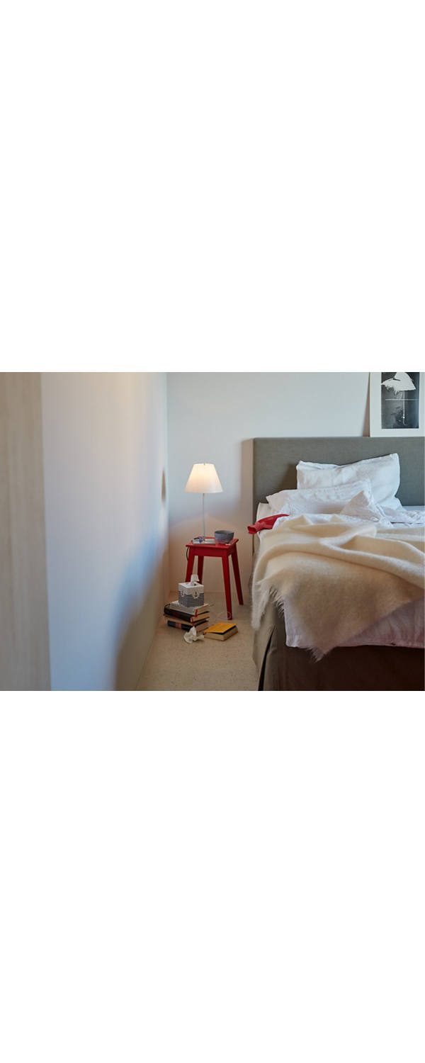 A burning bedside lamp stands next to the bed.