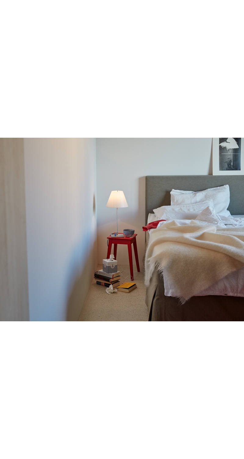 A burning bedside lamp stands next to the bed.