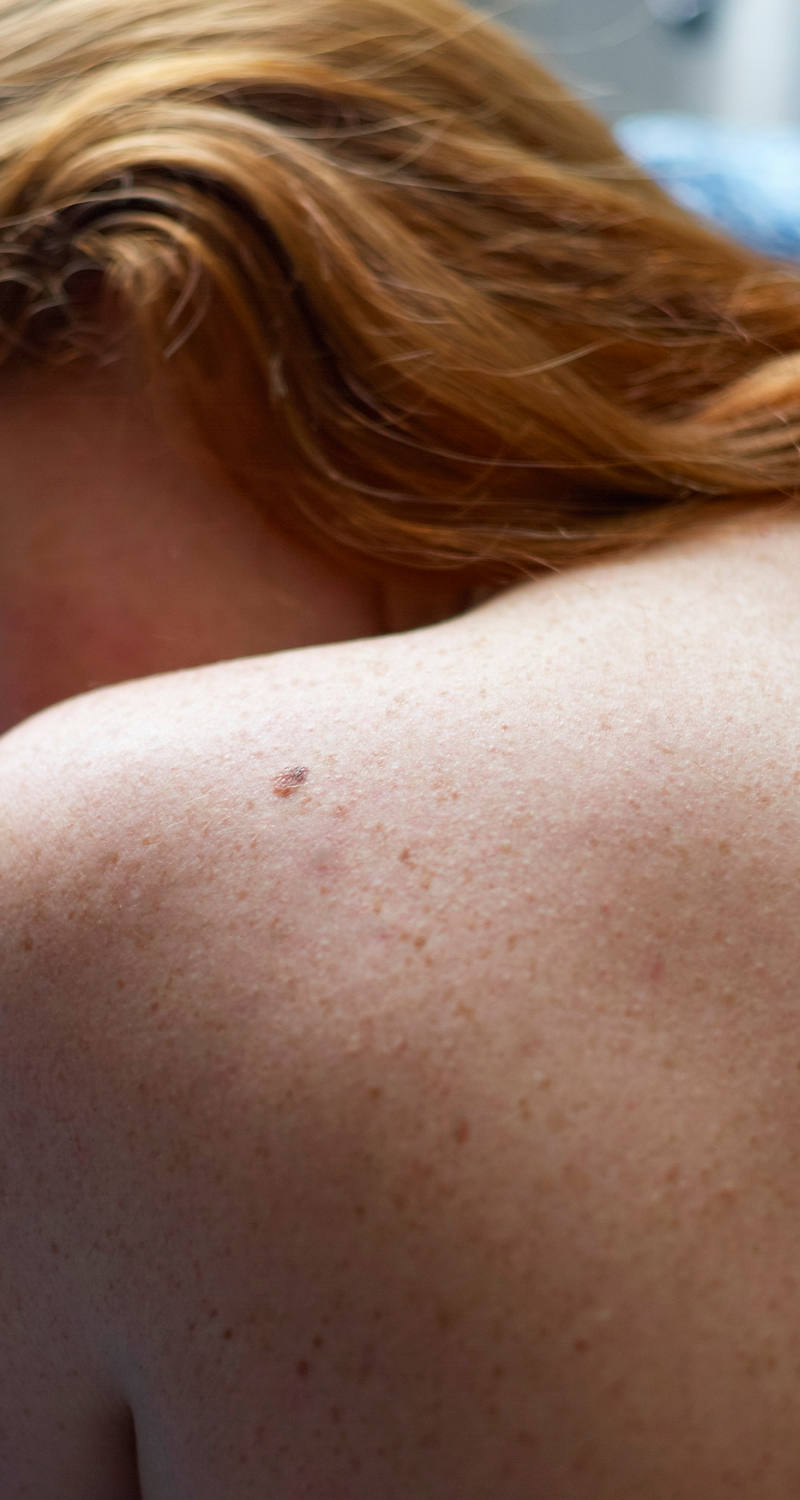 A woman lies on her left stomach, her back is visible.