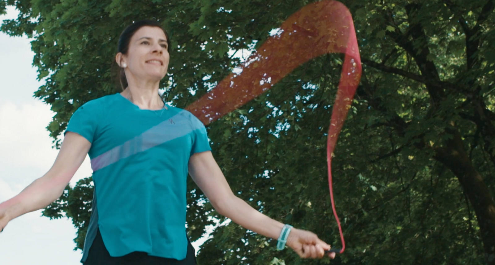 Eine Frau ist draussen in der Natur am Seilspringen.