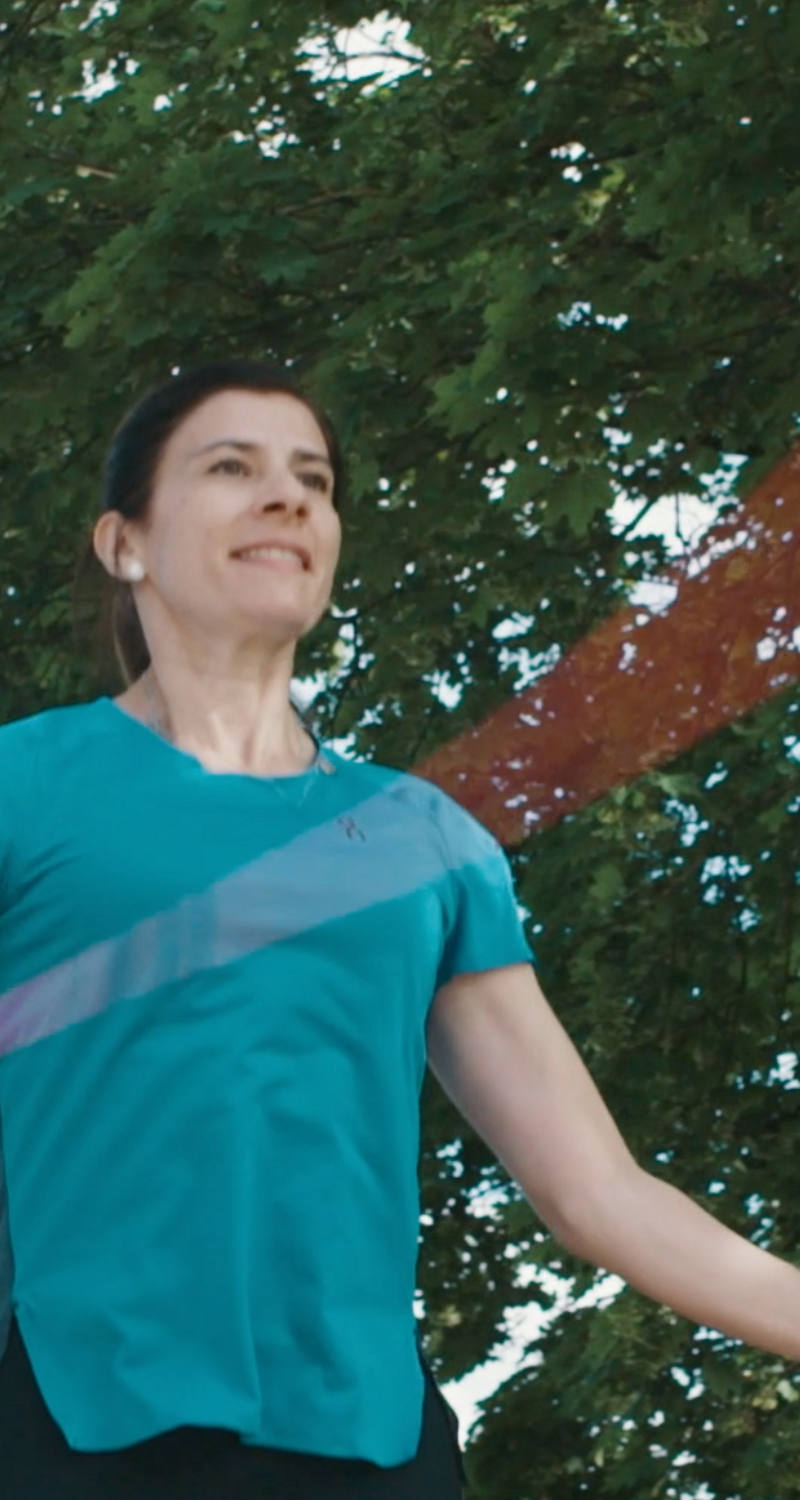 A woman is out in nature skipping.