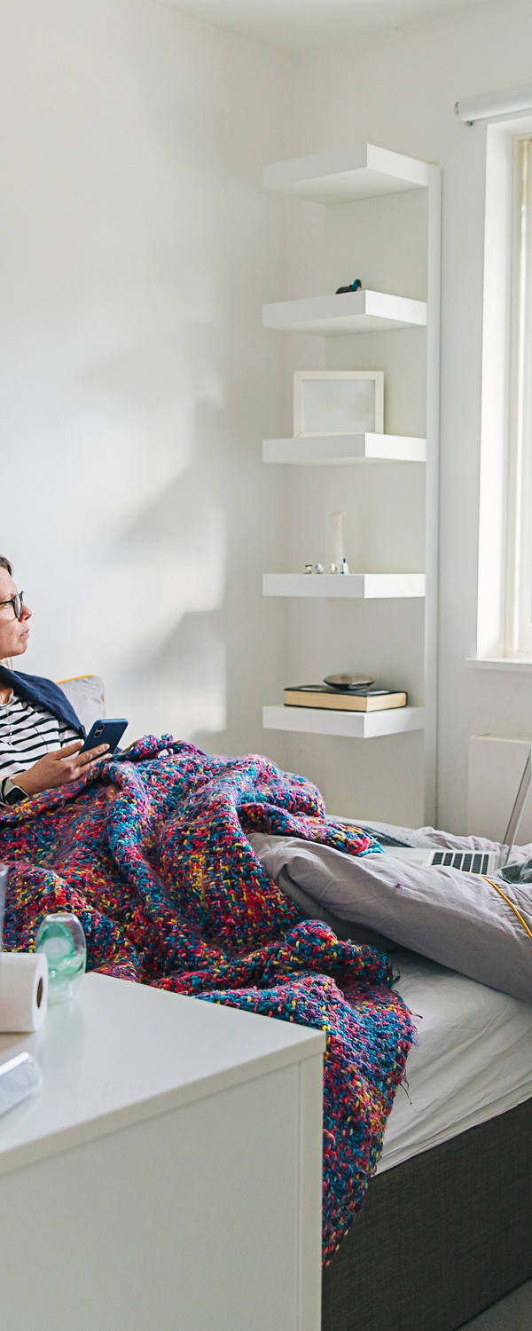 A woman is lying sick in bed and looking out the window.