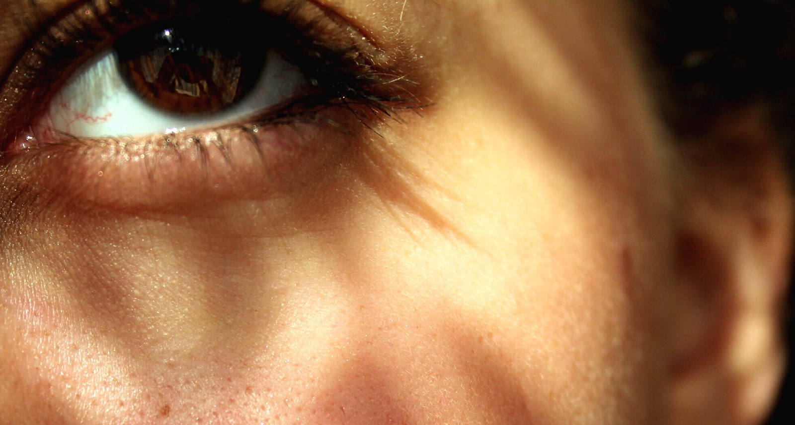 Close-up of the left side of the face of a woman shining the sun on her face.