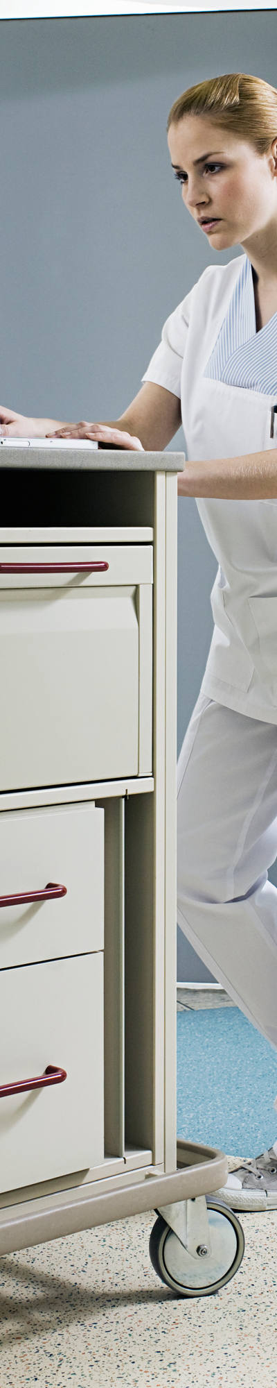 Nurse working on laptop in the hallway of the hospital.