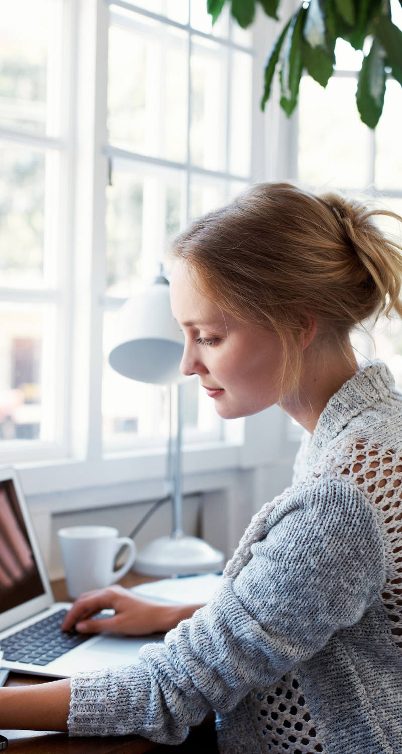 Woman working in front of window on laptop