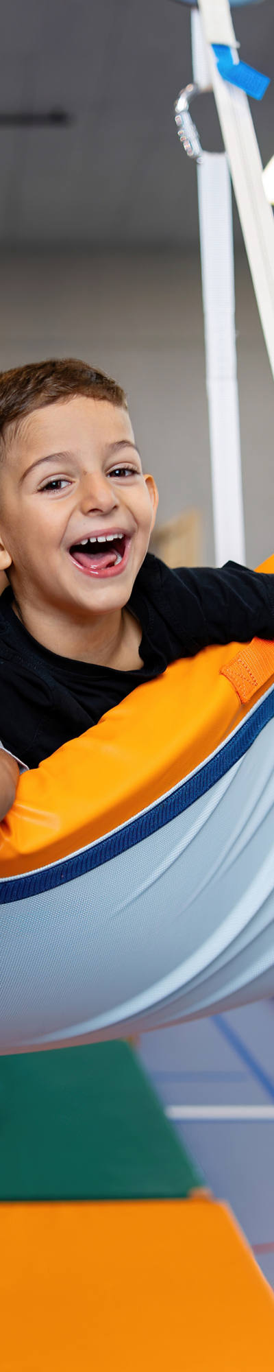 Due bambini allegri in età di scuola elementare giocano in una palestra e dondolano su un tappetino sospeso.