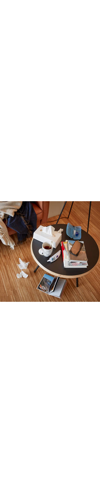 Table avec des ustensiles en cas de refroidissement tels qu’un thermomètre, du thé et une boîte Kleenex.