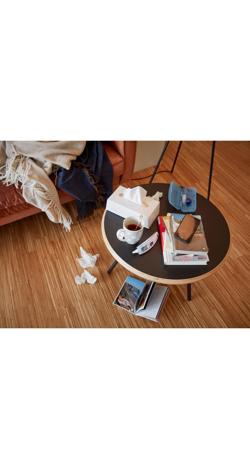 Tisch mit Erklältungsutensilien wie Fiebermesser, Tee und Kleenex-Box.