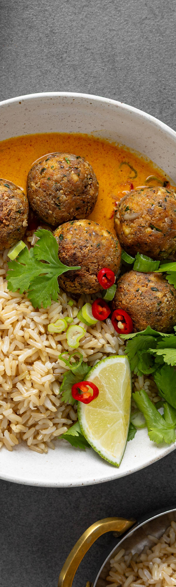 Tofu-Bällchen auf Reis gebettet und in einer Schale angerichtet mit Limette und Petersilie.