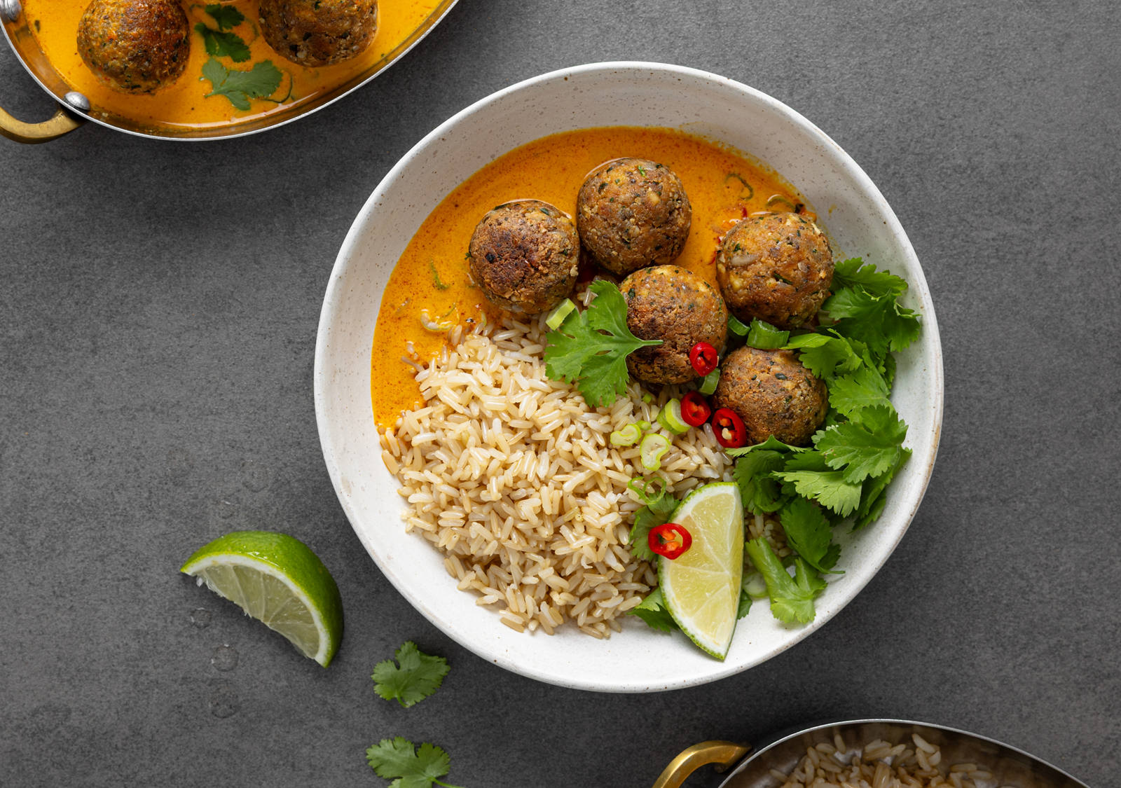 Tofu-Bällchen auf Reis gebettet und in einer Schale angerichtet mit Limette und Petersilie.