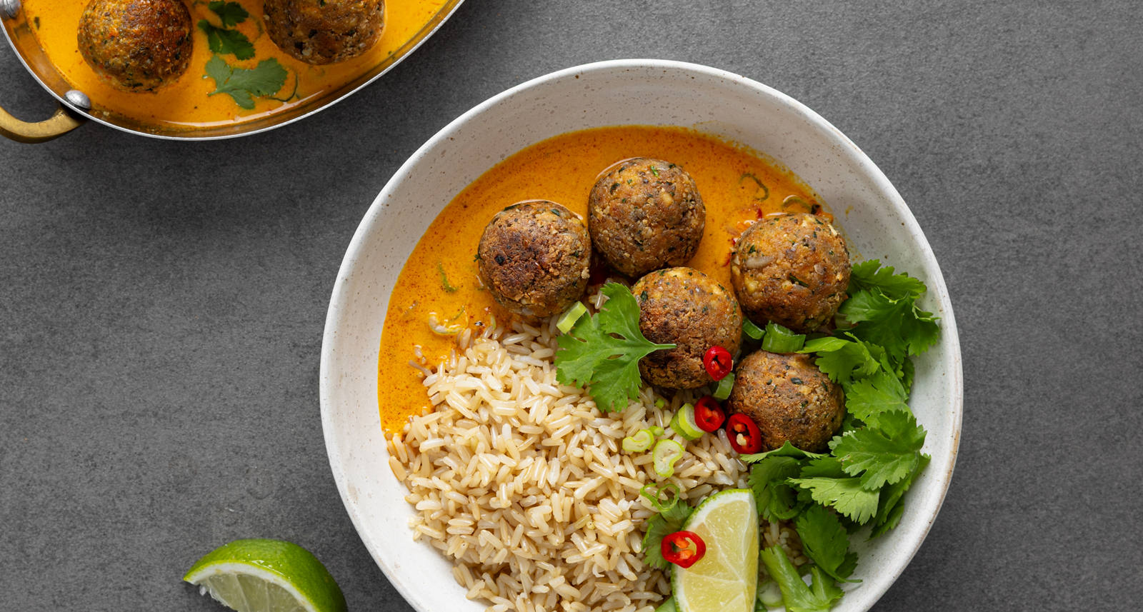 Boulettes de tofu posées sur du riz et disposées dans un bol avec du citron vert et du persil.