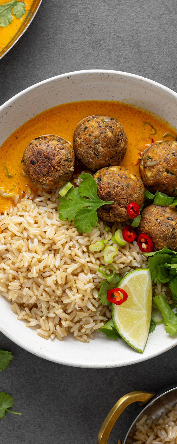 Tofu-Bällchen auf Reis gebettet und in einer Schale angerichtet mit Limette und Petersilie.