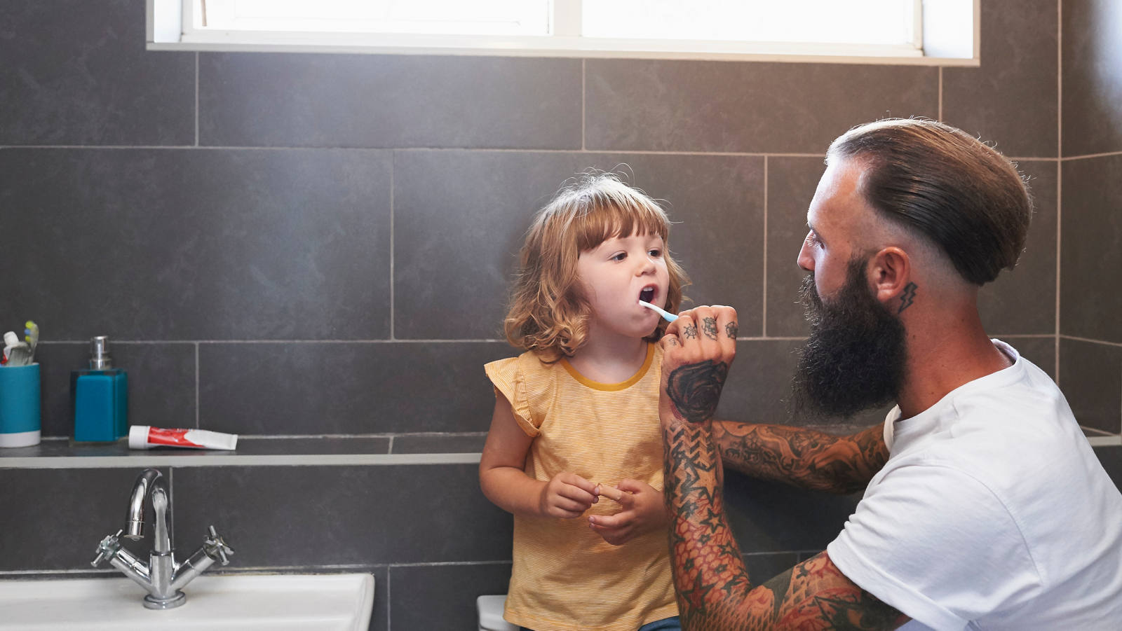Vater putzt Tochter die Zähne im Badezimmer