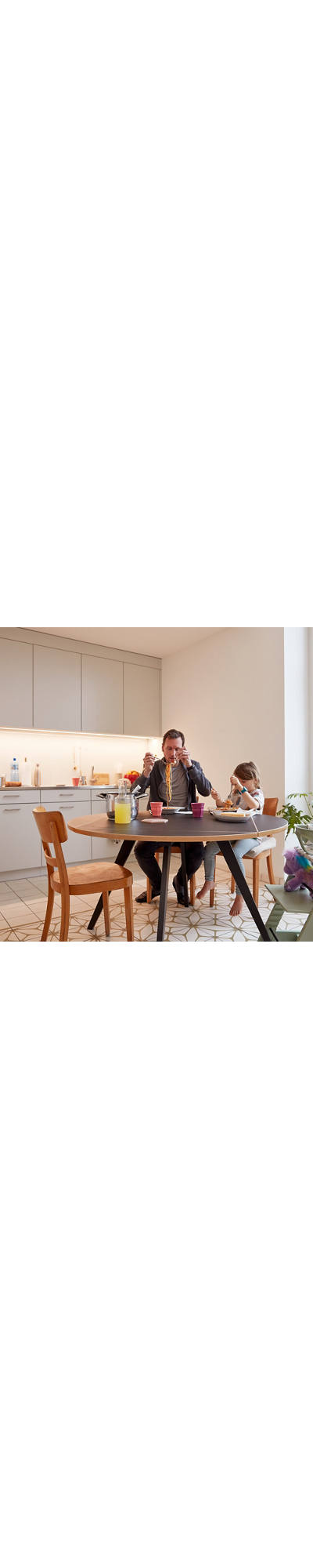 Vater und Tochter essen Spaghetti am Küchentisch