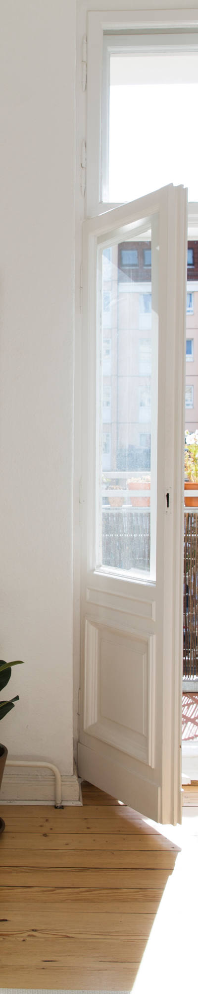Woman enjoys the sunshine in the middle of the balcony door of her apartment.