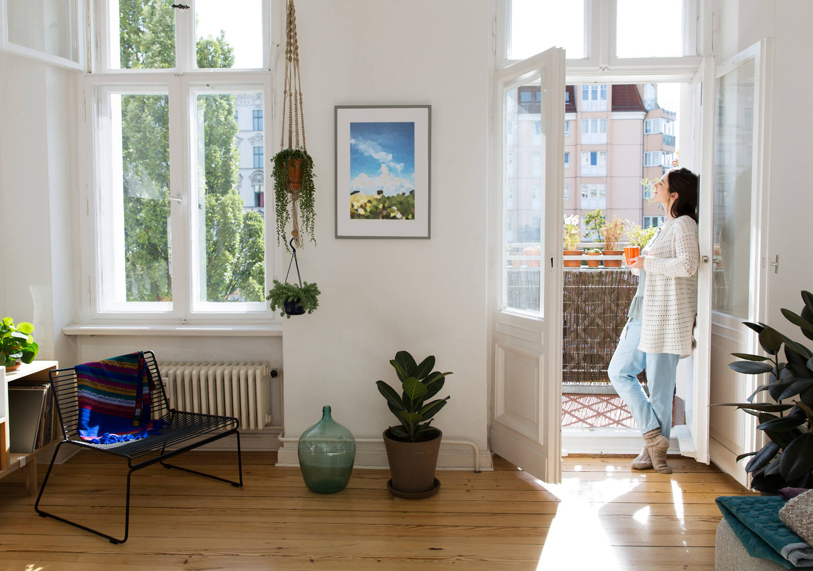 Frau geniesst die Sonnenstrahlen inmitten der Balkontüre ihrer Wohnung.