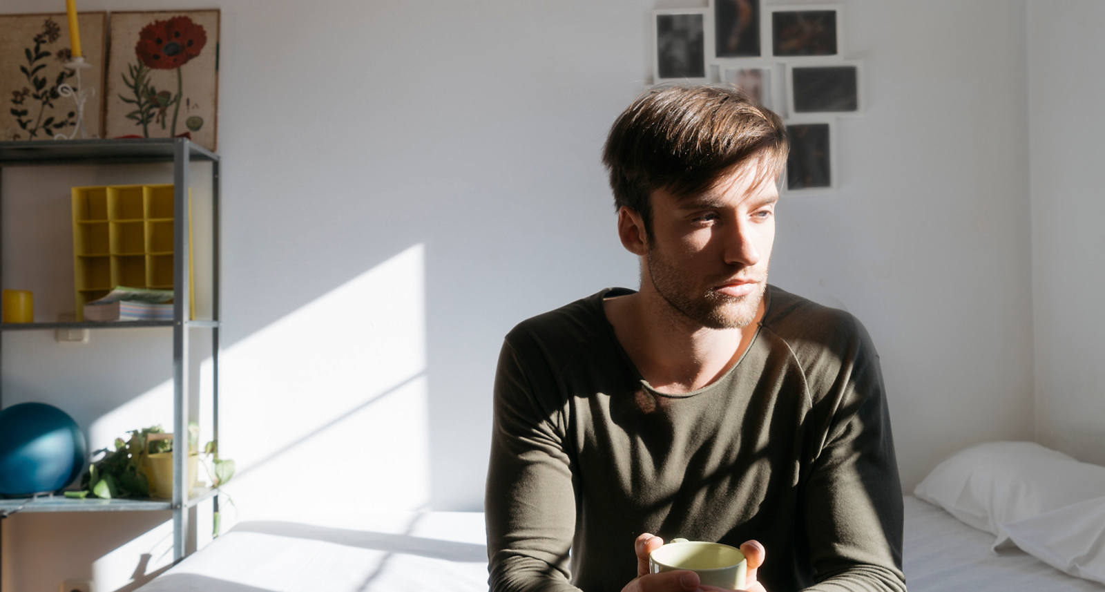 Un homme est assis sur son lit et regarde l’immensité en pensant.