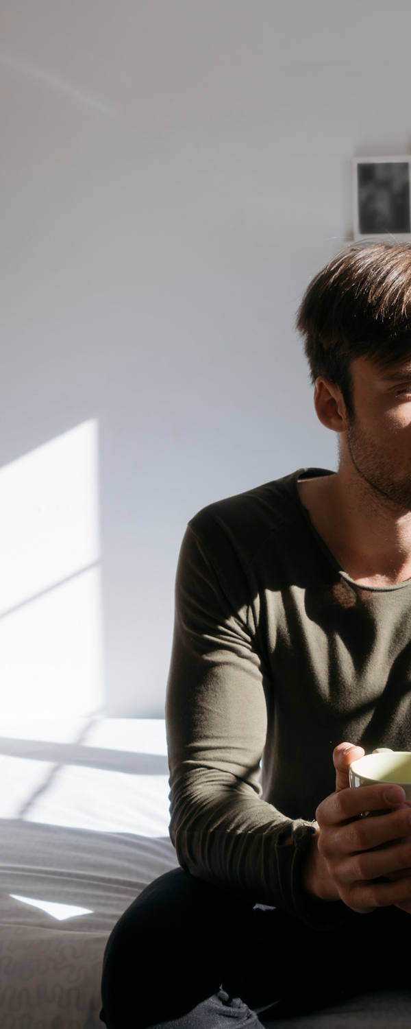 Un homme est assis sur son lit et regarde l’immensité en pensant.