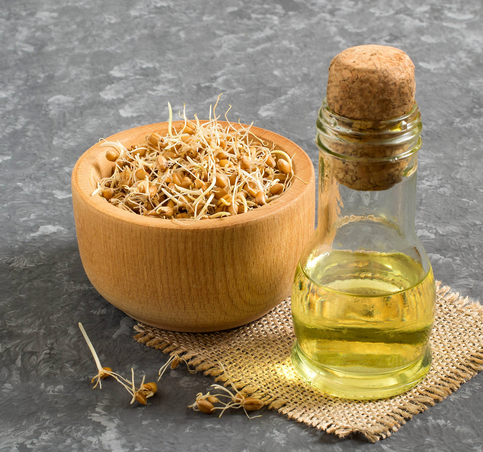 Wheat germ in a bowl and a bottle of wheat germ oil next to it.