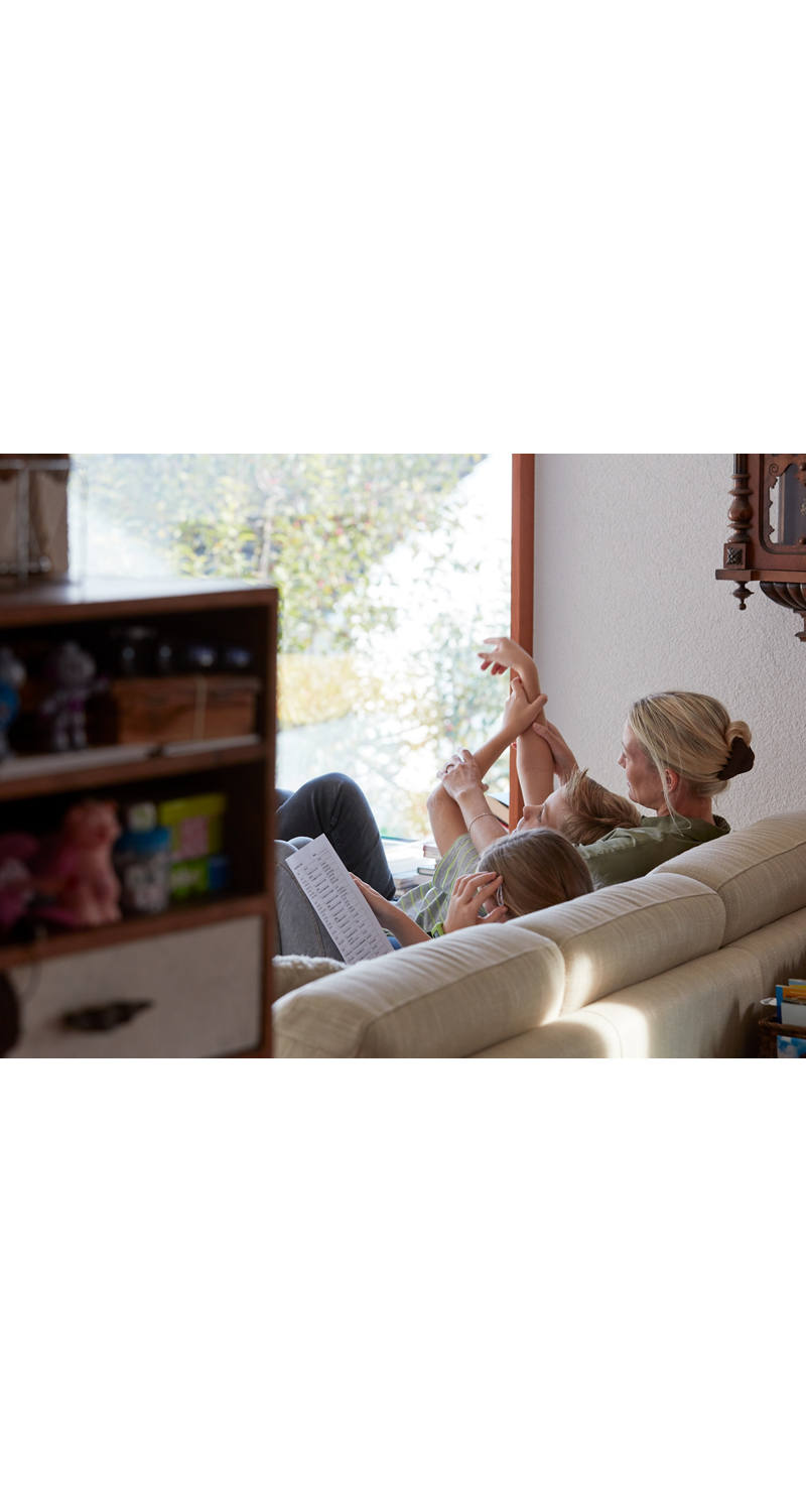 Mutter mit Kindern sitzen auf dem Sofa im Wohnzimmer.
